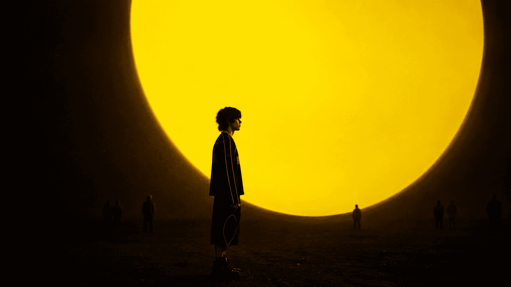 Kollateral campaign model silhouetted in front of a yellow circular light
